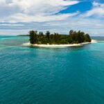 Aerial view of a tropical beach in Balabac, Palawan with clear turquoise water, palm trees, and boats, showing why travelers ask "is Balabac Palawan safe"