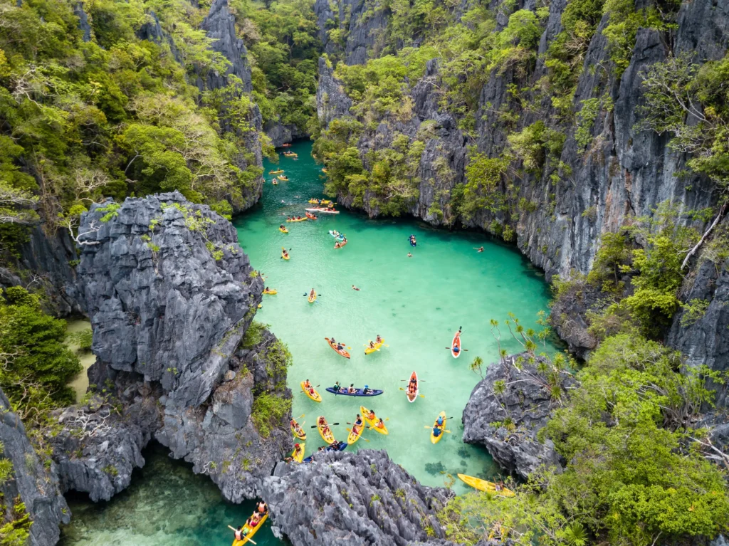 An aerial view of tourists kayaking in the turquoise waters of Small Lagoon, a top choice for where to go first in Palawan Philippines.