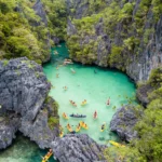 An aerial view of tourists kayaking in the turquoise waters of Small Lagoon, a top choice for where to go first in Palawan Philippines.