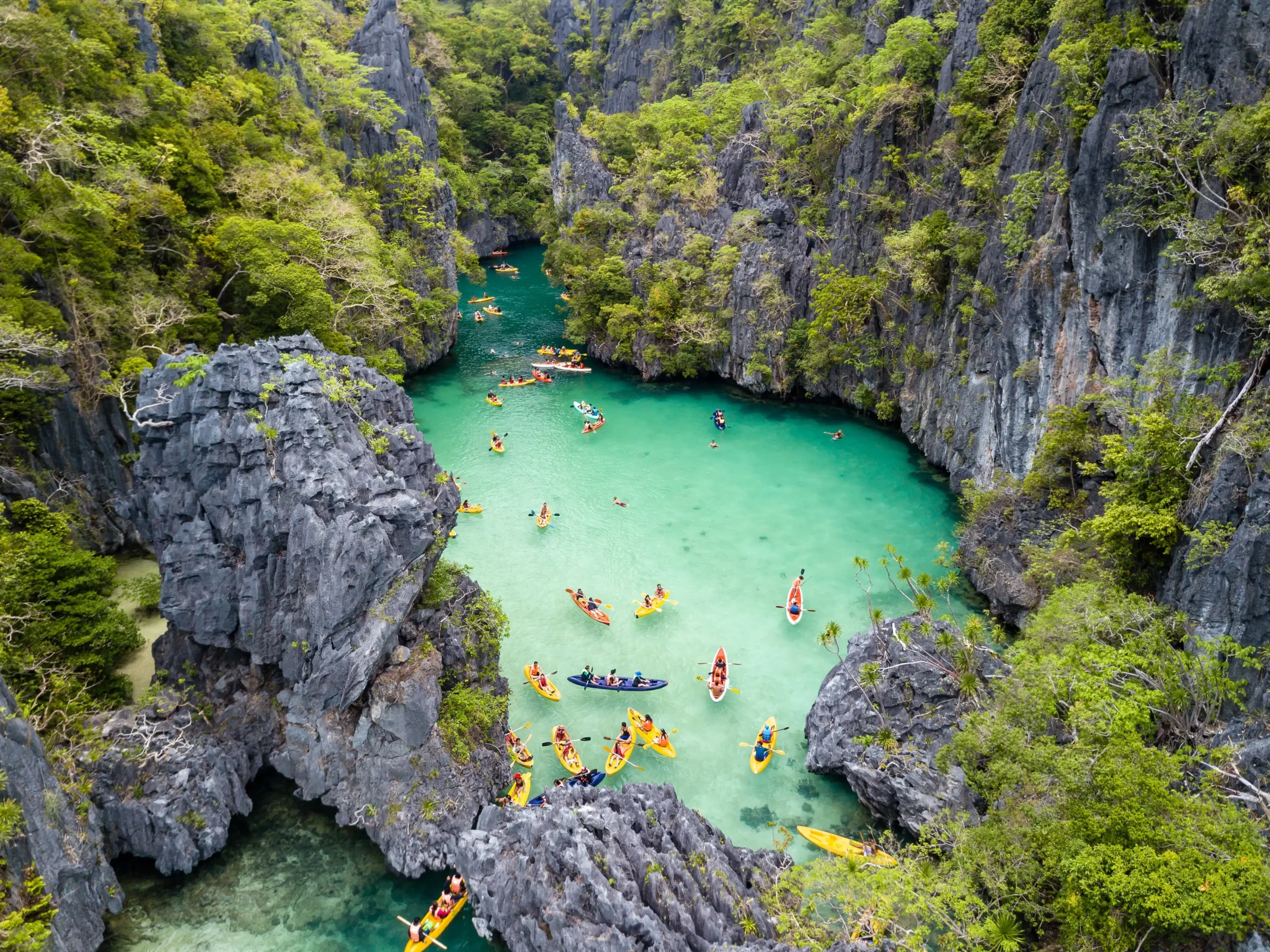 An aerial view of tourists kayaking in the turquoise waters of Small Lagoon, a top choice for where to go first in Palawan Philippines.