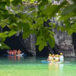 Tourists wearing life jackets and helmets ride in small boats near the cavernous limestone entrance of the underground river Palawan.