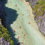 Aerial view of kayaking in Big Lagoon El Nido, revealing vibrant orange boats.