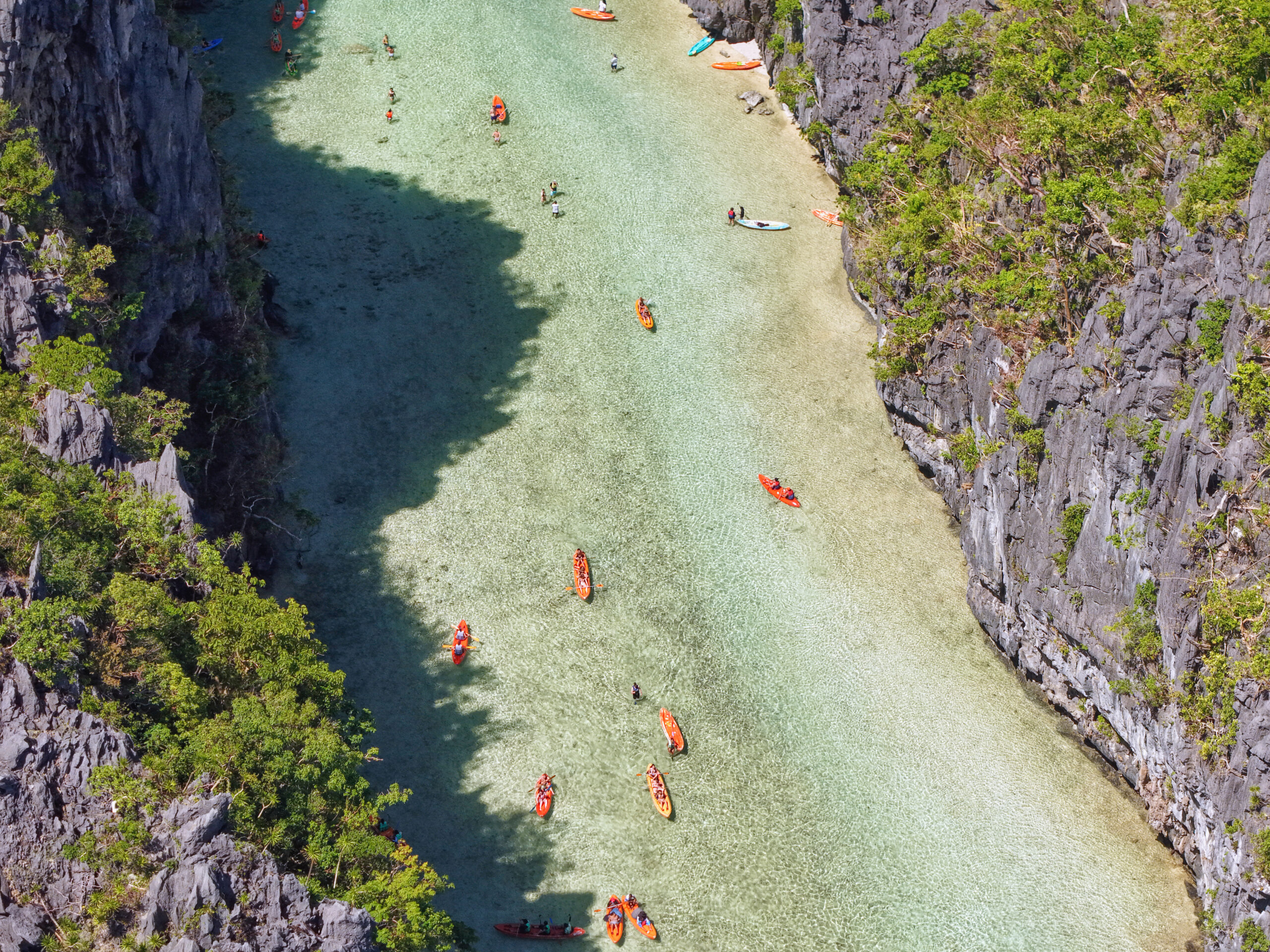 Aerial view of kayaking in Big Lagoon El Nido, revealing vibrant orange boats.